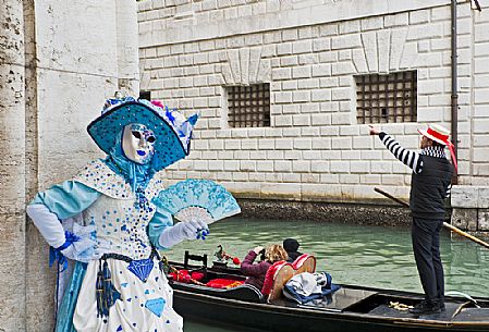 Mask and tourists in gondola near the Bridge of Sighs or Ponte dei Sospiri during the carnival in Venice, Italy, Europe