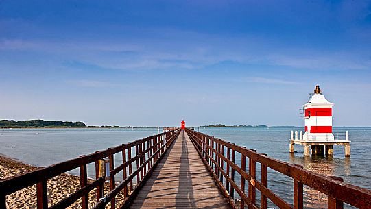 The pier of Punta Faro and the Faro Rosso lightouse in Lignano Sabbiadoro, Friuli Venezia Giulia, Italy, Europe