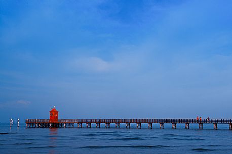 Tourists on the pier of Punta Faro lighthouse in Lignano Sabbiadoro at sunset, a beautiful seaside resort in Friuli Venezia Giulia, Italy, Europe