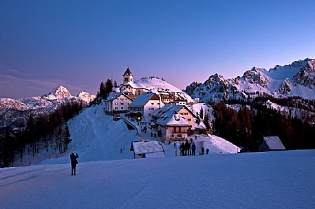 Tourists at the iconic village of Monte Lussari mount in a winter sunset, Tarvisio, Julian Alps, Friuli Venezia Giulia, Italy, Europe