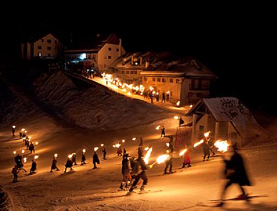 Costumed skiers descend from Monte Lussari mount with the torch lit on New Year's day. Tarvisio, Julian alps, Friuli Venezia Giulia, Italy, Europe
