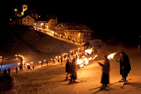 Costumed skiers descend from Monte Lussari mount with the torch lit on New Year's day. Tarvisio, Julian alps, Friuli Venezia Giulia, Italy, Europe
