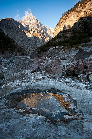 Monte Castello in the Friulian Dolomites natural Park is reflected in a pool of frozen water, Friuli Venezia Giulia, Italy, Europe