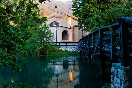 The sanctuary of the Holy Trinity in Polcenigo is reflected in the waters of the Livenza river near its source. Italy