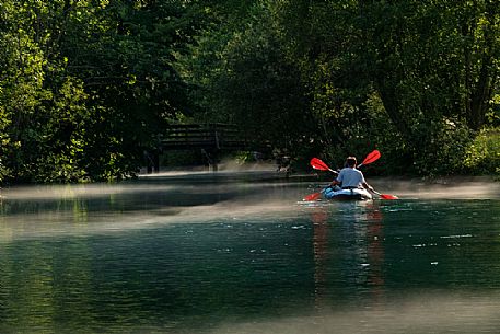 Tourists in canoes enjoy the panorama of the Livenza river near the source called 