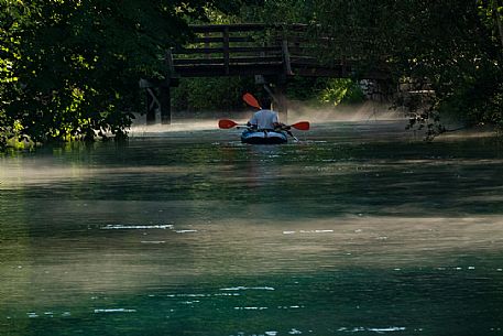 Tourists in canoes enjoy the panorama of the Livenza river near the source called 