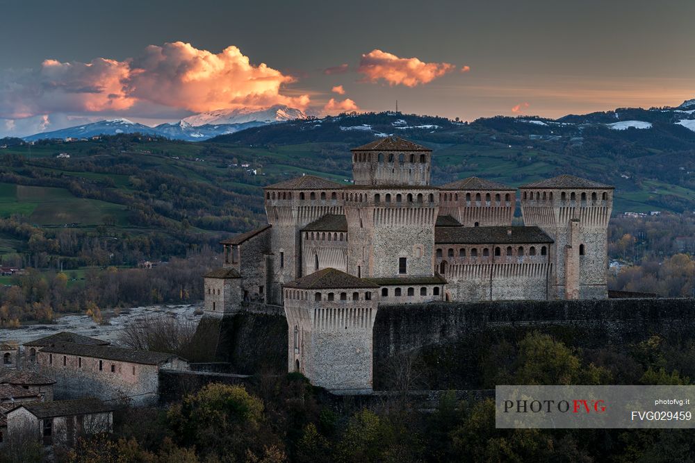 Torrechiara castle at twilight and in the background the Cusna mount, Langhirano, Emilia Romagna, Italy