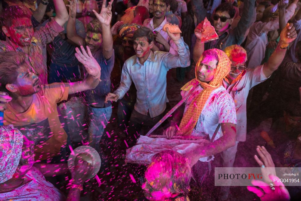 People celebrating holi festival, the festival of colors, in a temple in Rajasthan, dancing and singing, throwing colors to each other, Jajpur, India