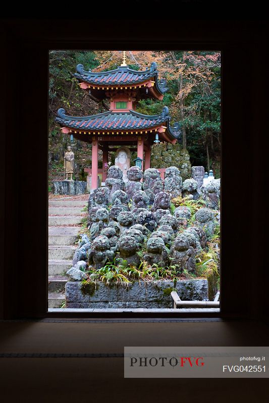 Some of the 1200 Rakan statues in Otagi Nenbutsu-ji temple in Arashiyama framed by the temple door, Kyoto, Japan