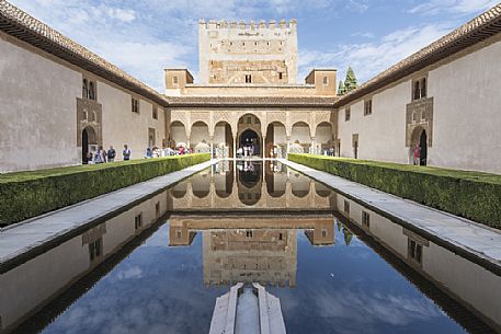 Comares palace reflects in the pond of Arrayanes Patio, part of Nazaries Palace, in the Alhambra complex, Granada, Spain