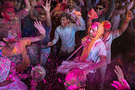 People celebrating holi festival, the festival of colors, in a temple in Rajasthan, dancing and singing, throwing colors to each other, Jajpur, India