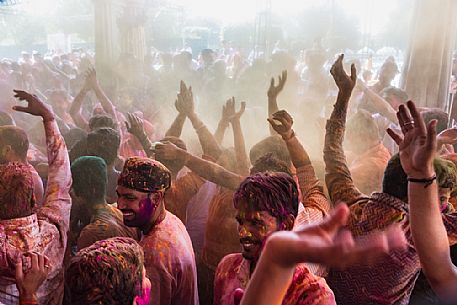 People celebrating holi festival, the festival of colors, in a temple in Rajasthan, dancing and singing, throwing colors to each other, Jajpur, India