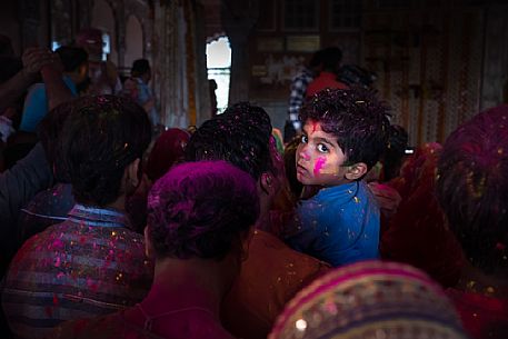 Portrait of a child with colors on his face, during the celebration of holi festival, the festival of colors in a temple in Rajasthan, Jaipur, India