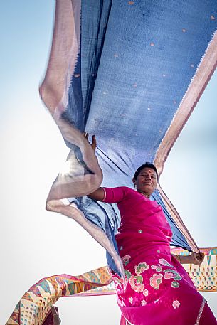 Portrait of indian woman selling sari with great backlight effect enhancing the colors of the textiles, Varanasi, Uttar Pradesh, India