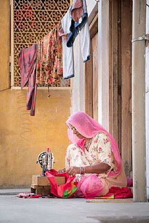 Indian woman sewing in front of her house door, Jaisalmer, Rajasthan, India