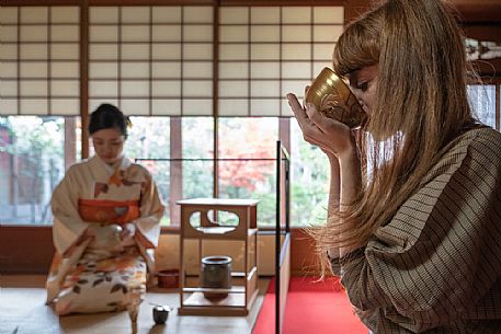 Woman tasting tea during a traditional Japanese tea ceremony, Kyoto, Japan
