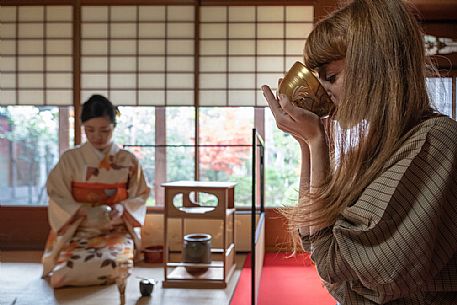 Woman tasting tea during a traditional Japanese tea ceremony, Kyoto, Japan
