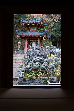 Some of the 1200 Rakan statues in Otagi Nenbutsu-ji temple in Arashiyama framed by the temple door, Kyoto, Japan