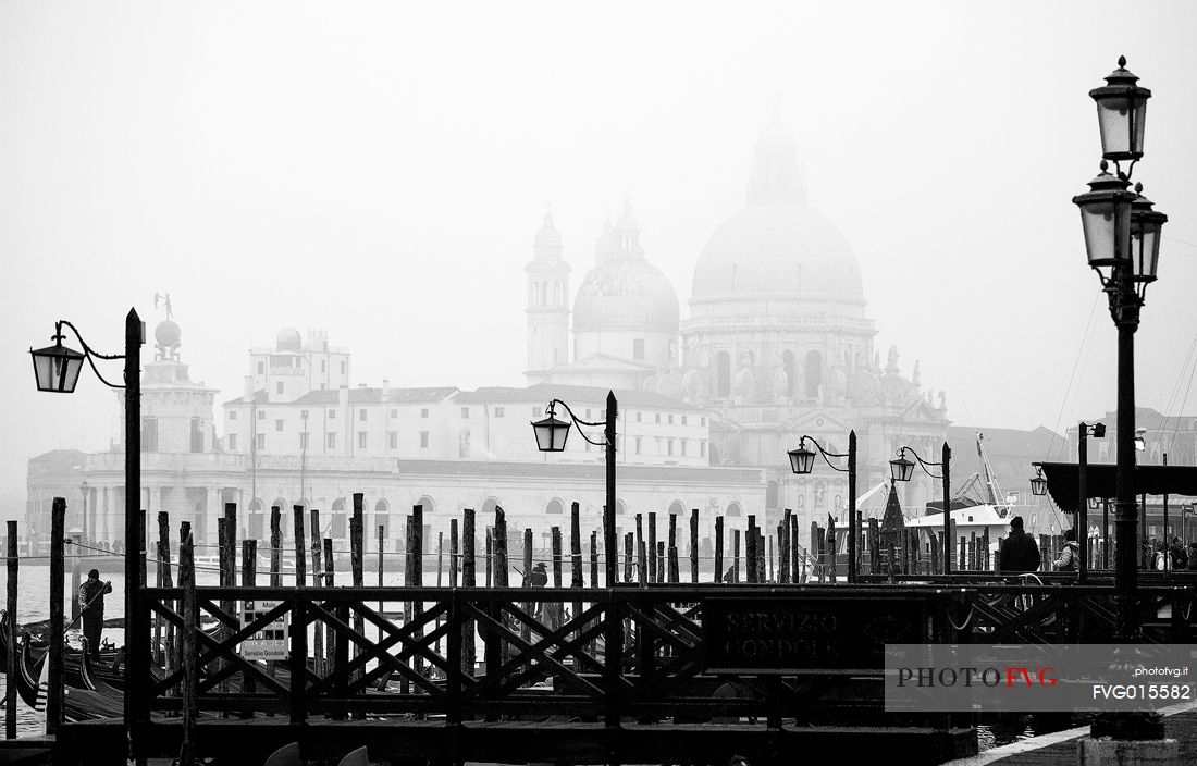 Venetian gondolas with the Basilica of St Mary of Health (commonly known simply as the Salute )cover by fog 