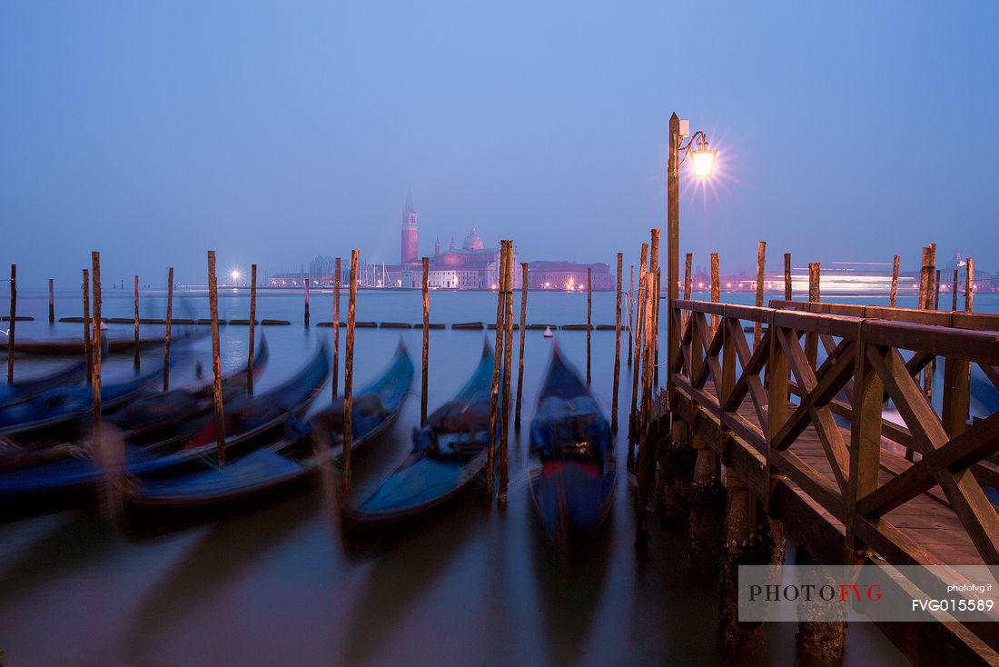 Evening's lights on the gondolas in St. Mark's basin in Venice, in the background the Basilica of St Giorgio Maggiore.