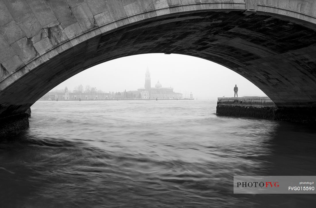 View of Basilica of St Giorgio Maggiore photographed from under the bridge in a foggy day