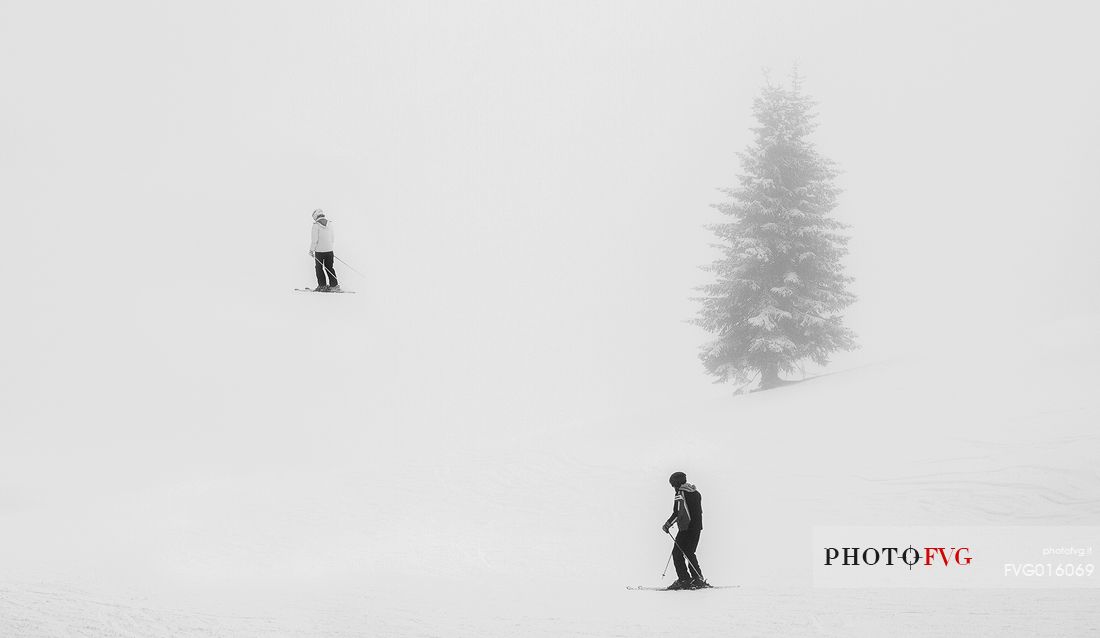 Skiers in the fog on the slopes of Croda Rossa