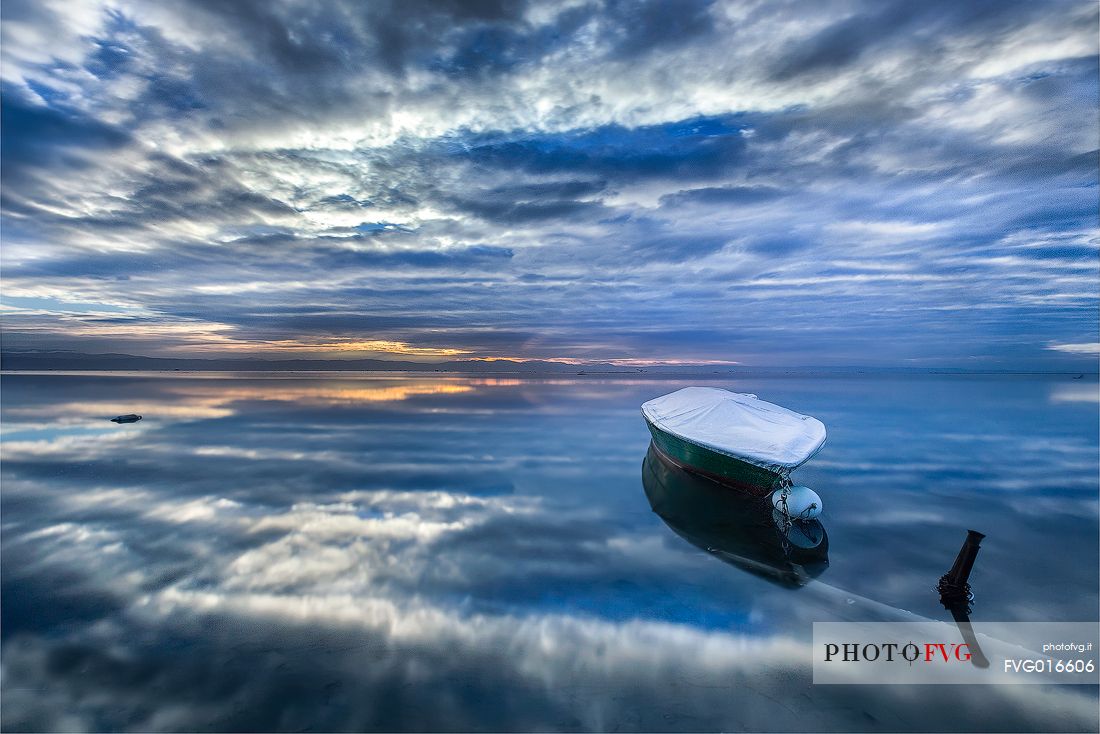 Reflections of an overcast summer sunrise on the lagoon of Grado