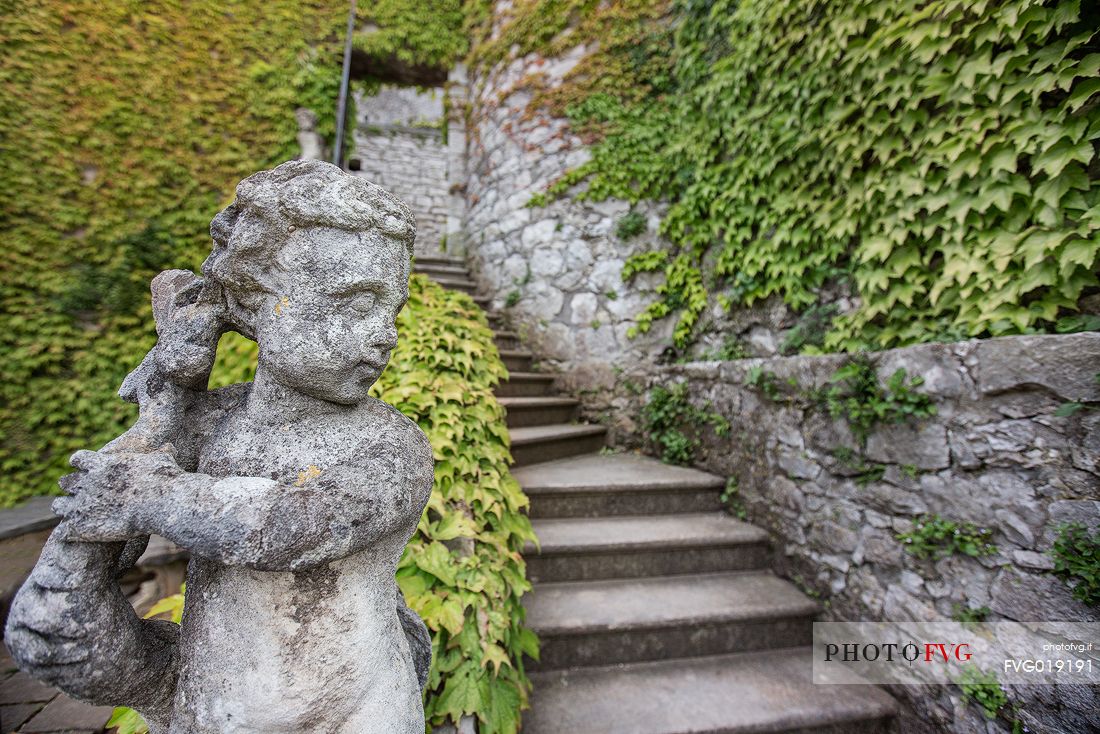A green corner of the park of the castle of Duino in Trieste embellished with one of the many statues of the park