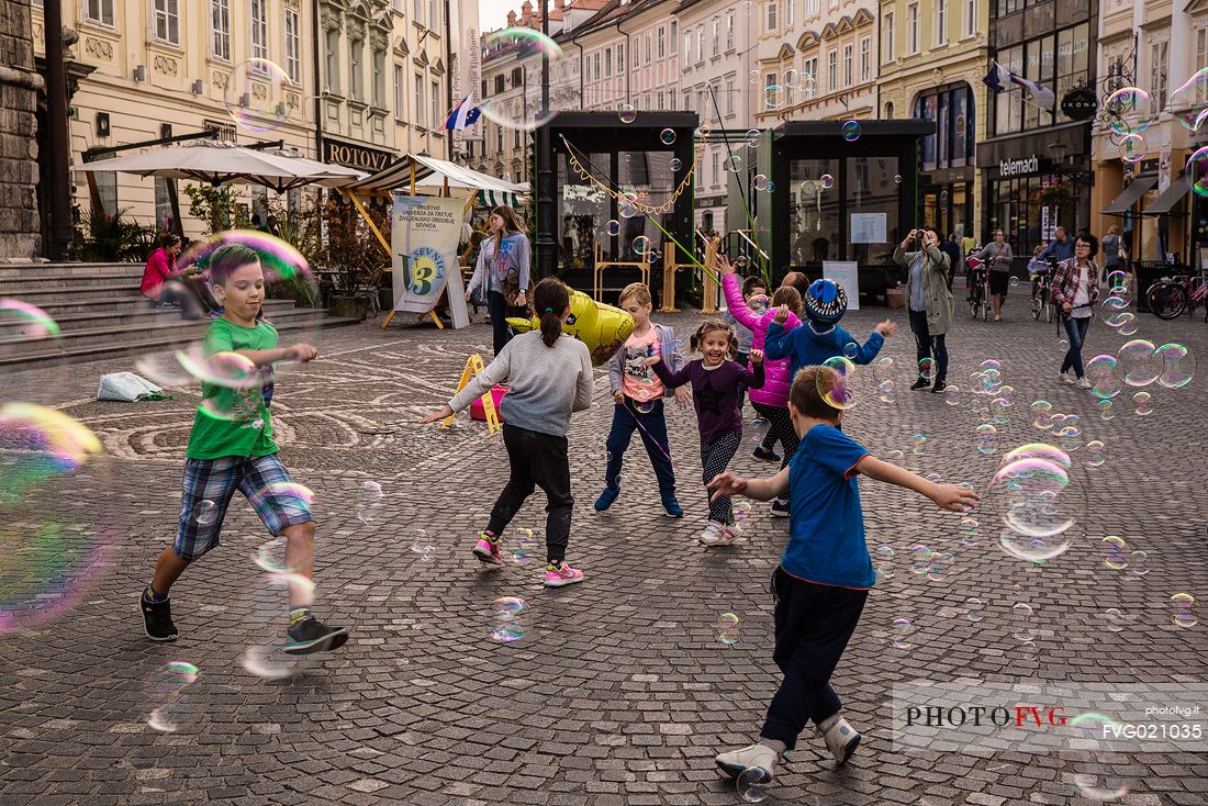 Children play with bubbles in the square in Lubiana, Slovenia, Europe