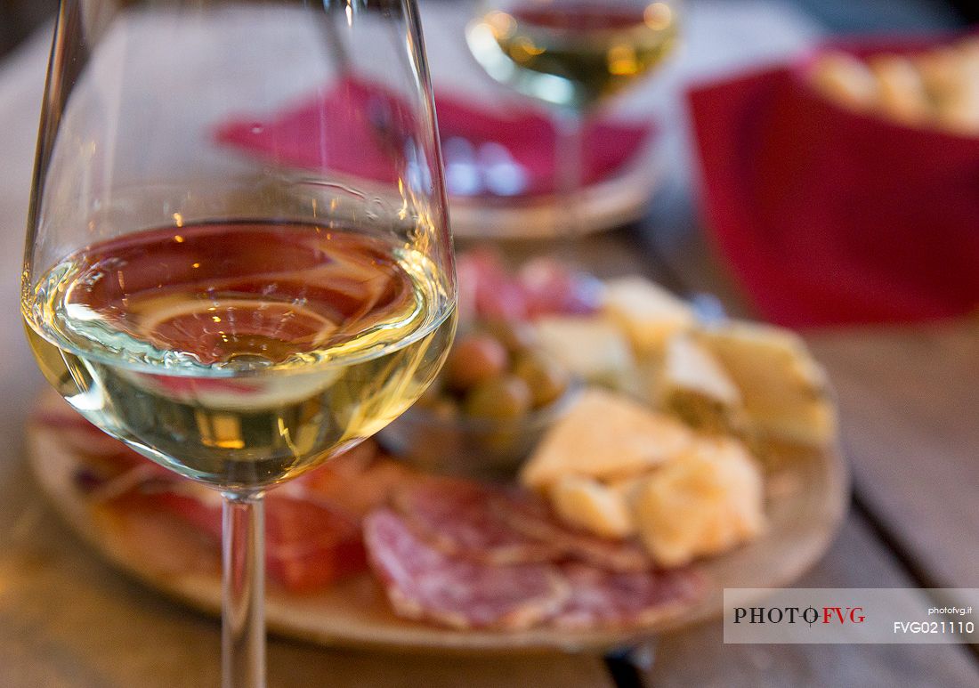 Cutting board of ham, salami and cheese with two glasses of white wine from Friuli