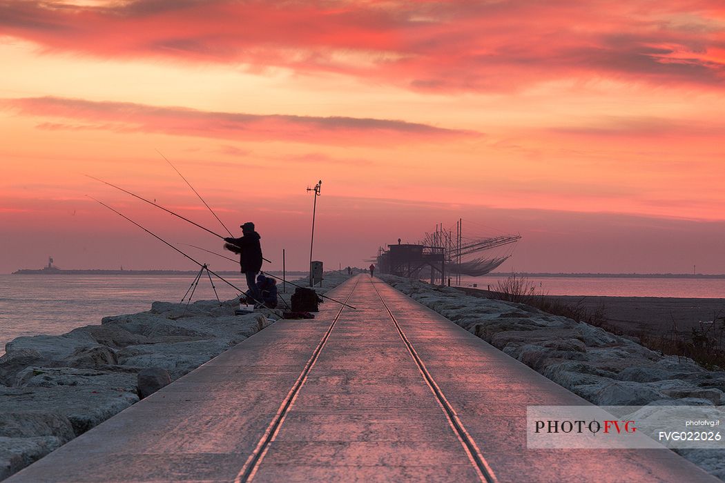 Fishermen at dawn along the pier of Sottomarina, Chioggia, venetian lagoon, Italy