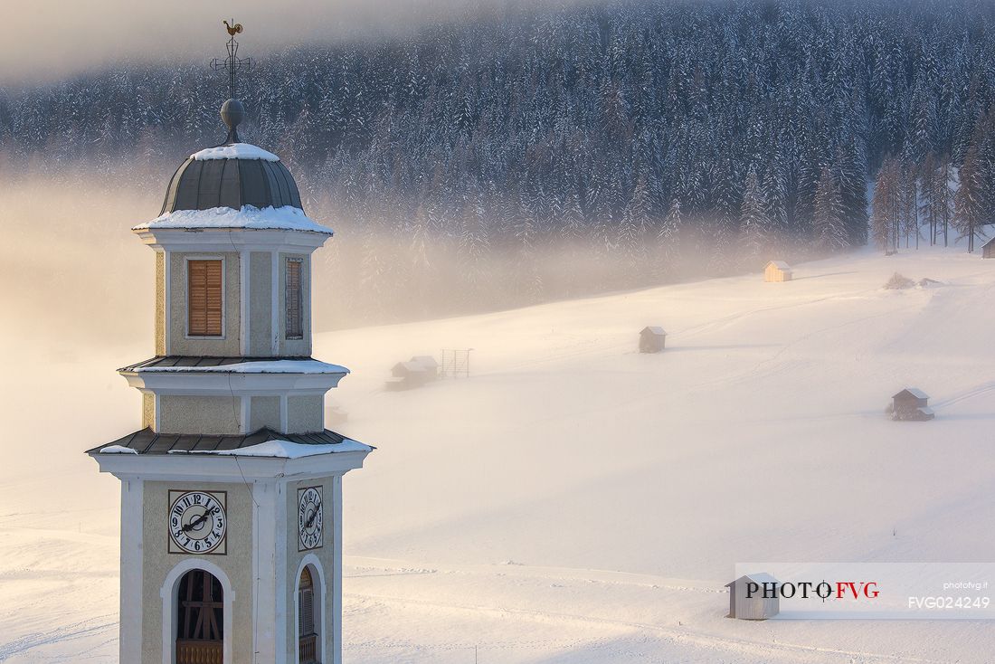 The parish church of Sesto and barns in the background during sunrise winter, Sesto, dolomites, Italy