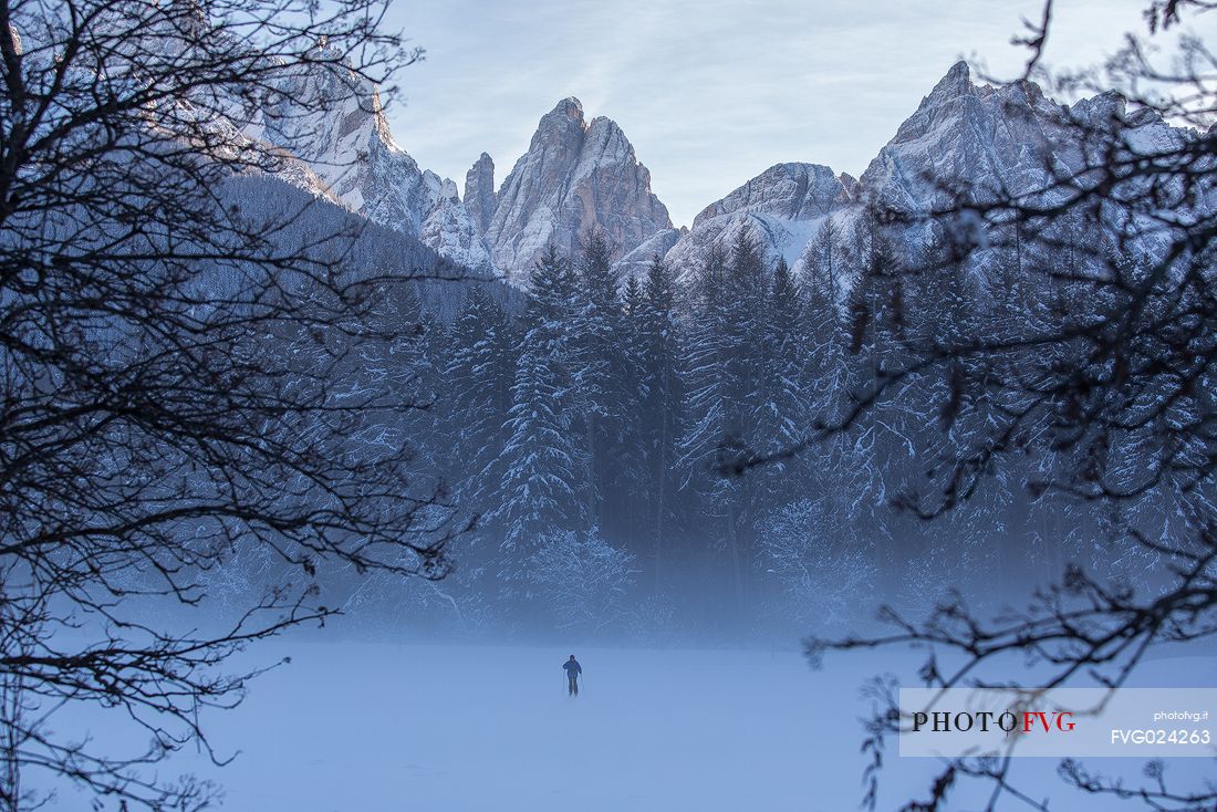 Cross country skier under a thick winter fog with the Croda dei Toni on background, Dolomites of Sesto natural park, Italy