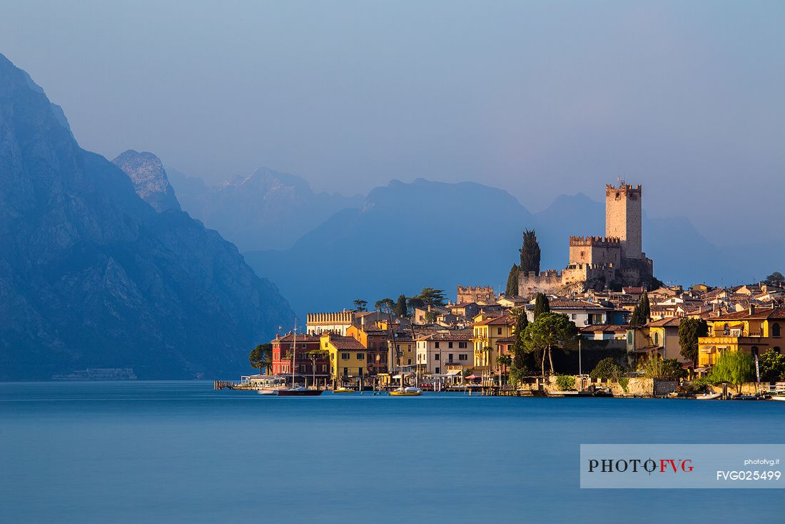 The small medieval village of Malcesine and the Scaligero castle on Garda lake illuminated at sunset, Italy