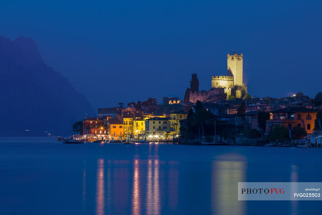 The small medieval village of Malcesine and the Scaligero castle illuminated during the blue hour, Garda lake, Italy