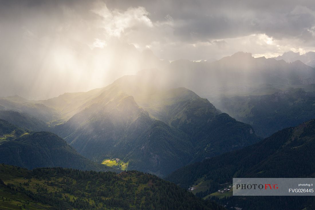 Light rays filter through a cloud in a thunderstorm illuminating the valley in front of the Nuvolau refuge, Dolomites, Cortina D'Ampezzo, Italy