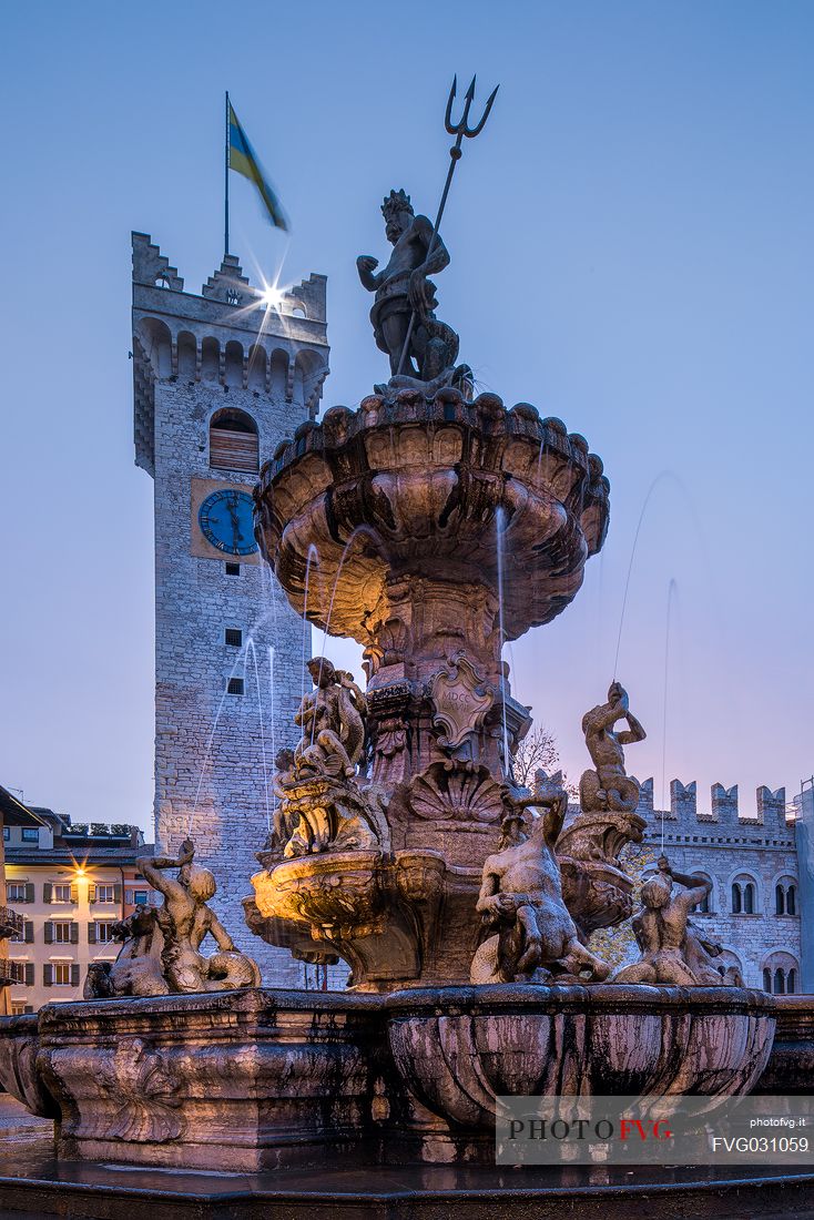 The fountain of Nettuno and the Civic tower in Duomo square at sunset, Trento, Trentino Alto Adige, Italy