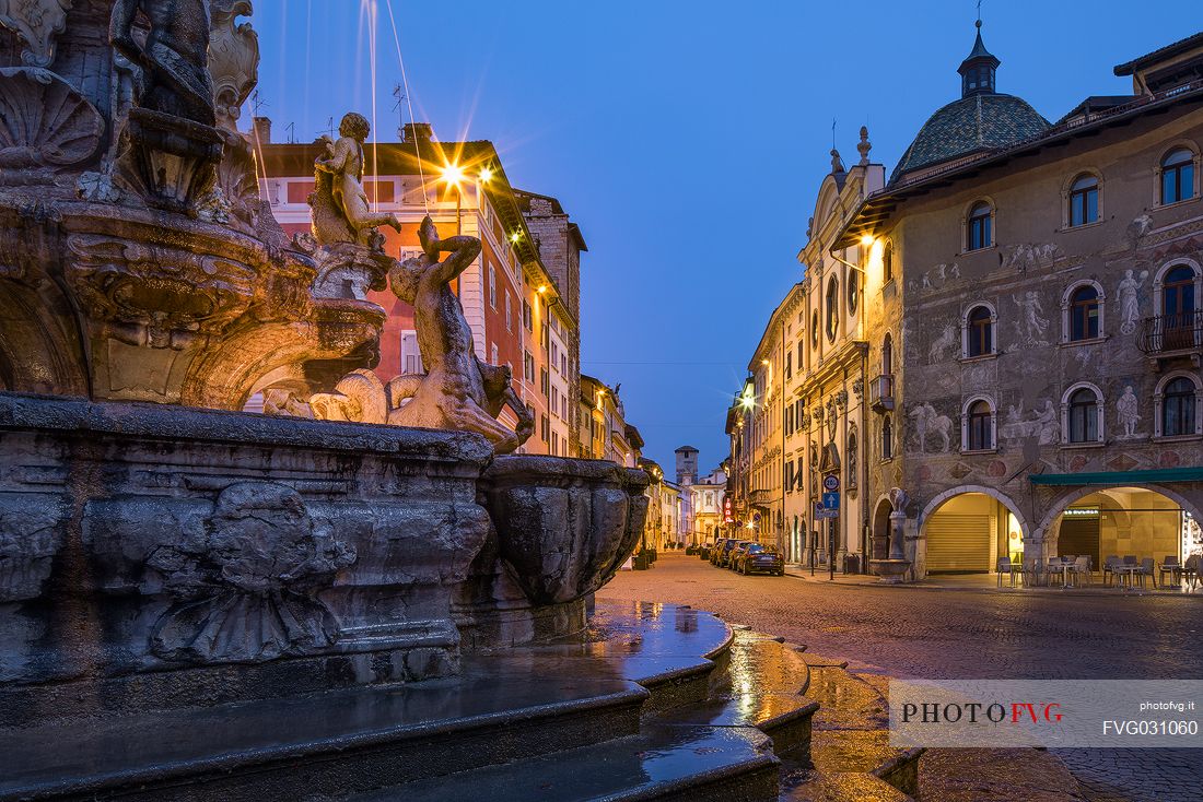 Detail of the fountain of Nettuno, on background the palaces in the Duomo square at twilight, Trento, Trentino Alto Adige, Italy