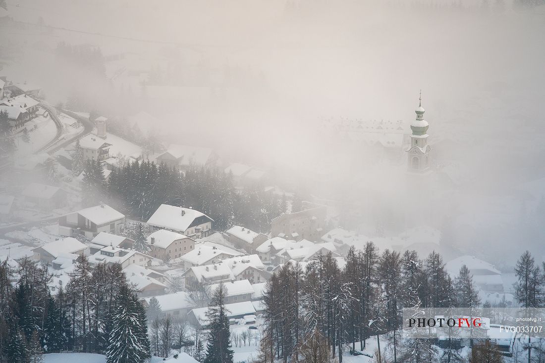 The bell tower of the church of Dobbiaco appears from above the clouds, Pusteria valley, dolomites, Trentino Alto Adige, Italy, Europe