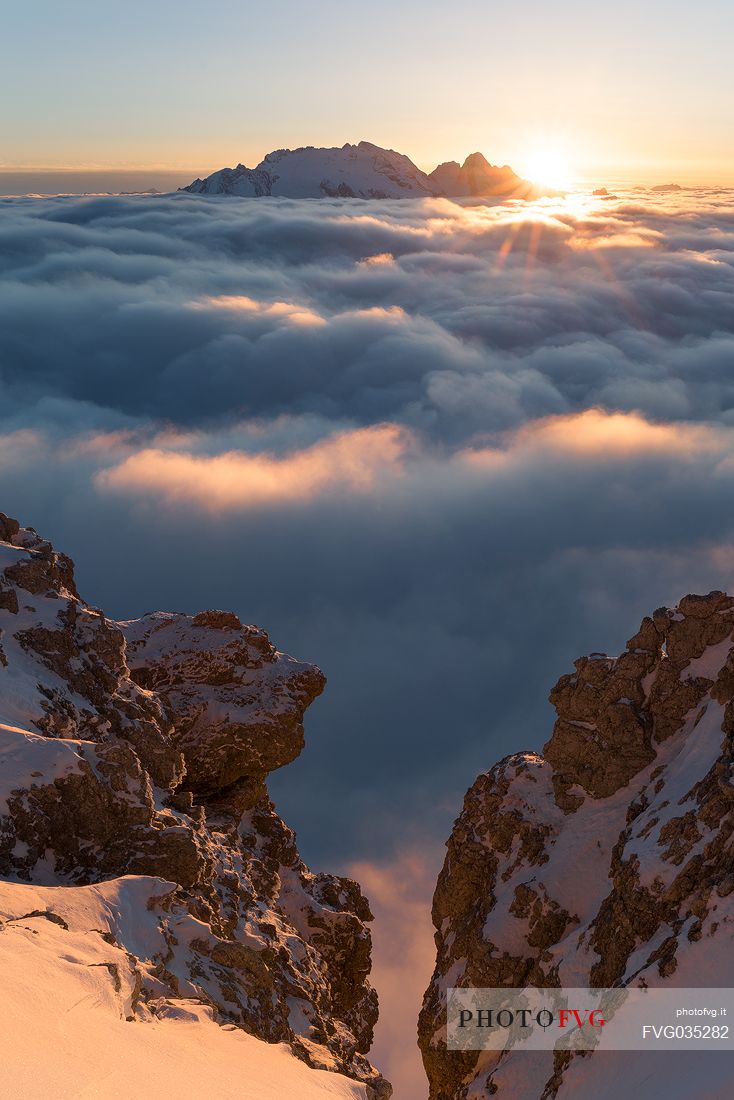 The sun sets behind the Marmolada peak over a sea of clouds, Cortina d'Ampezzo, dolomites, Veneto, Italy, Europe