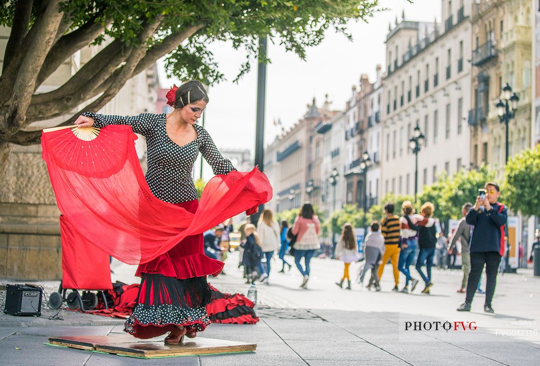 Woman in traditional costume dances flamenco in the streets of the Barrio Santa Cruz, Seville, Spain, Europe