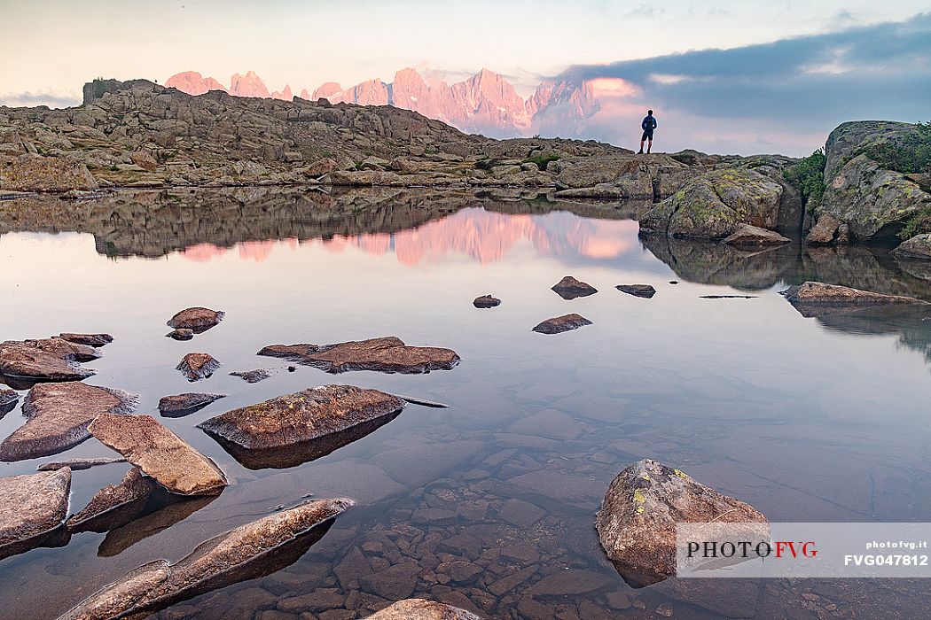 Hiker at the Juribrutto lakes with Pale di San Martino mountain group at sunset, San Martino di Castrozza, dolomites, Trentino Alto Adige, Italy, Europe