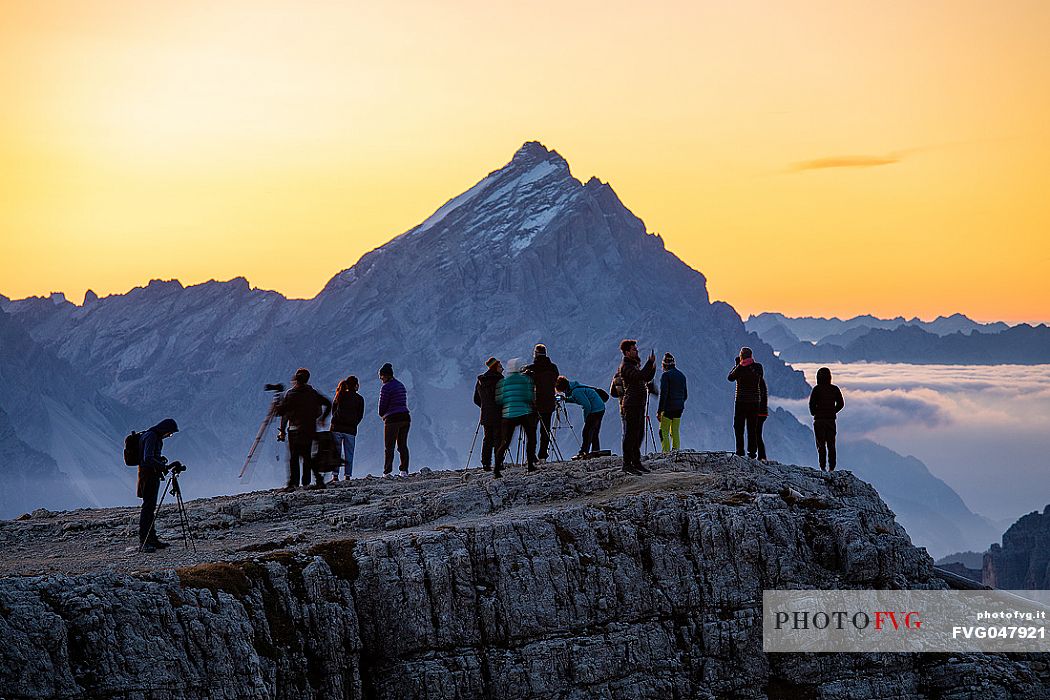 Tourists photograph the sun rising nearby Lagazuoi refuge, on background the Antelao Mount, Cortina d'Ampezzo, Veneto, Italy, Europe