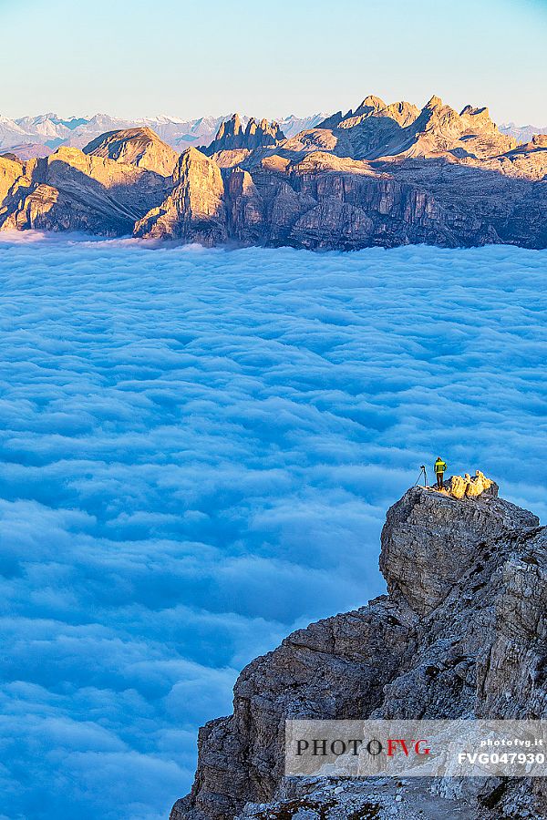 Photographer looks the sunrise towards the Odle mountain group and the clouds wrap around the landscape nearby Lagazuoi Refuge, Cortina d'Ampezzo, Veneto, Italy, Europe