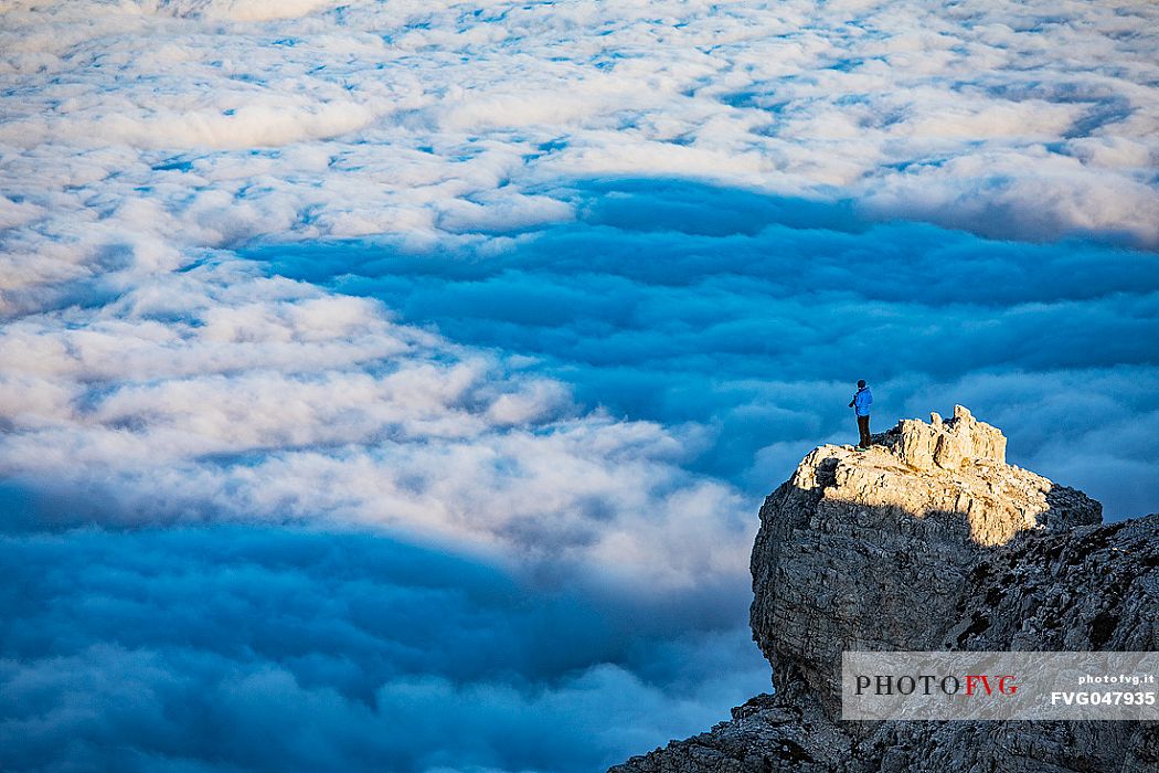 Photographer sourranded by a low clouds sea on the top of Lagazuoi mount, Cortina d'Ampezzo, dolomites, Veneto, Italy, Europe