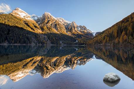 The Anterselva lake framed by the gold of larch trees in a morning of autumn 