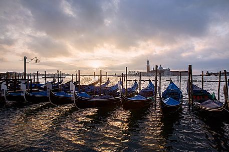 Venetian gondolas during a soft sunrise with the Basilica of St Giorgio Maggiore on background