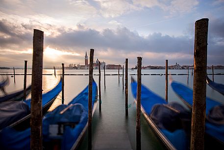 Venetian gondolas during a soft sunrise with the Basilica of St Giorgio Maggiore on background