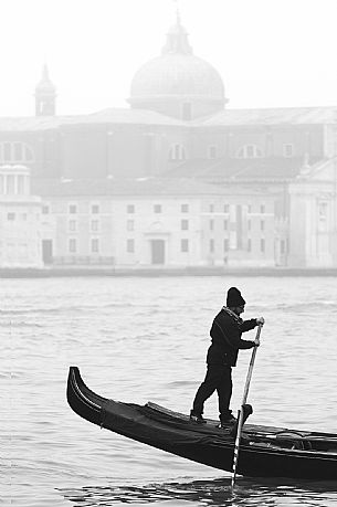The gondolier paddling through the fog with the Basilica of St Giorgio Maggiore on background