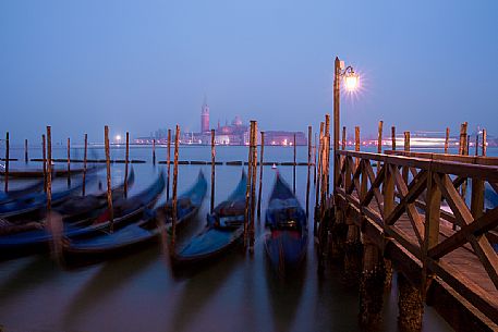 Evening's lights on the gondolas in St. Mark's basin in Venice, in the background the Basilica of St Giorgio Maggiore.